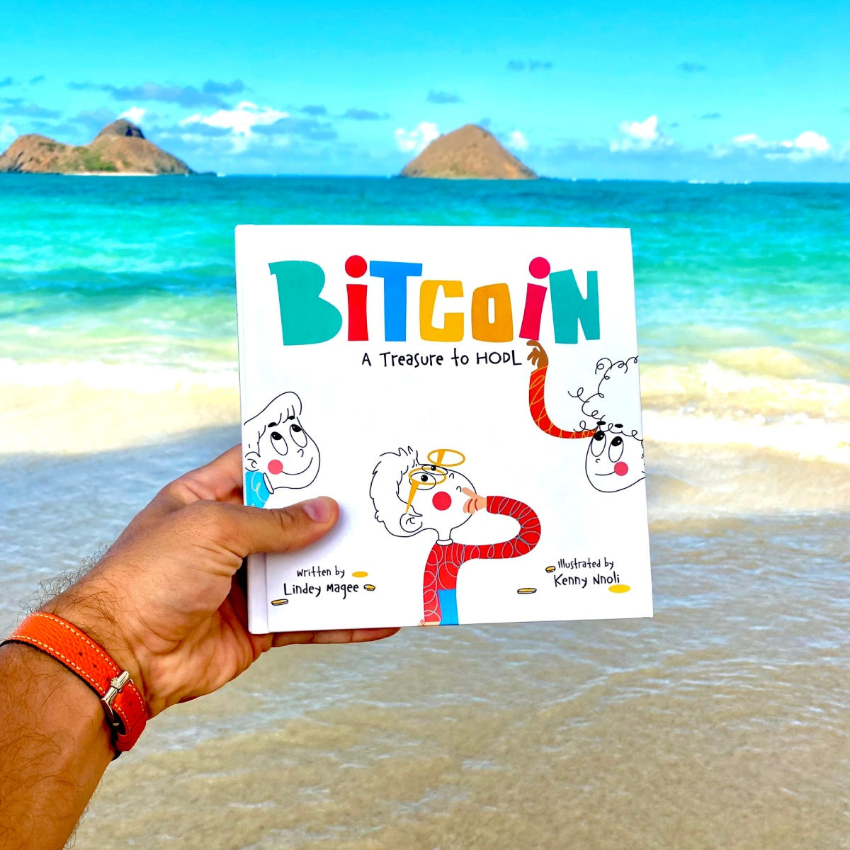 Hand holding a book titled 'Bitcoin: A Treasure to Hold' with a beach in the background
